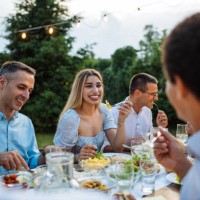 groupe multiethnique de personnes mangeant dans la cour arrière le soir d’été et s’amusant - garden decoration photos et images de collection