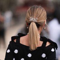 Guest is seen outside Chanel show wearing a silver Chanel bow hair detail and black Chanel top with white camellia details during the Womenswear...