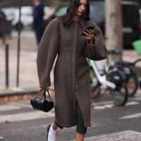 Guest is seen outside Chanel show wearing brown oversized round shaped coat, black leather handbag, white socks and black ballet flats during the...