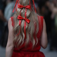 Guest is seen outside Khaite show wearing red bows in her hair, red dress on September 09, 2023 in New York City.
