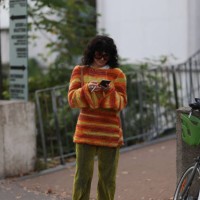 Guest is seen Outside Peter Do show wearing orange colored Loewe sunnies, red, orange and yellow colored knit sweater, green velvet pants and red...