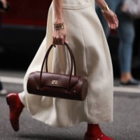 Guest is seen outside Tibi show wearing beige colored cotton dress with free arms, golden chunky bracelet, brown round shaped handbag woith golden...
