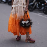 Guest is seen outside Zimmermann show wearing lilac Oakley sunnies, silver chain, white and orange ombre colored dress, beige hairy Fendi Baguette...