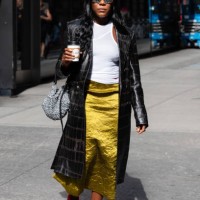 Guest is seen wearing a black coat, white top, green skirt, red mesh shoes, silver sunglasses and carrying a silver bag outside the Carolina Herrera...