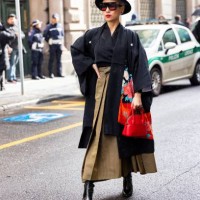 Guest is seen wearing a black hat, black and red sunglasses, a black shirt, a black and flower printed scarf, a red leather bag, a khaki long skirt...