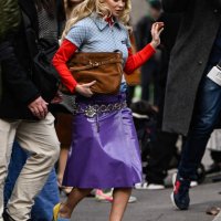 Guest is seen wearing a blue and red Miu Miu shirt, purple skirt, chain belt, brown bag and yellow and black heels with light blue Miu Miu socks...