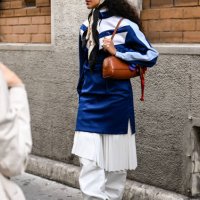Guest is seen wearing a blue and white Lacoste jacket, white panel skirt white pants and white boots with Lacoste brown bag and white had and...