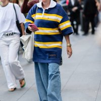 Guest is seen wearing a blue and yellow top, blue denim pant, white sneakers, brown sunglasses and carrying a white bag outside the Michael Kors show...
