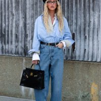 Guest is seen wearing a blue shirt, blue denim pant, black lace heels, black hat and carrying a black bag outside the COS show during New York...