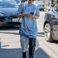 Guest is seen wearing a blue top, black boots, white sunglasses and carrying a white bag outside the COS show during New York Fashion Week on...