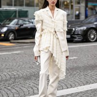 Guest is seen wearing a cream Rokh ruffled top, white Rokh pants and brown shoes outside the Rokh show during the Womenswear Fall/Winter 2025/2026 as...