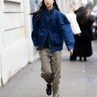 Guest is seen wearing a denim puffy bomber jacket, a black shirt, black leather loafers and military green trousers outside Marni show during the...