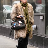 Guest is seen wearing a faux fur tan coat, black bag, black pants, black shoes and green scarf outside the Christian Siriano show during NYFW F/W...