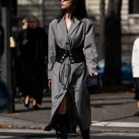 Guest is seen wearing a gray trench coat, black and silver belt, black boots and black sunglasses outside the Miu Miu show during the Womenswear...