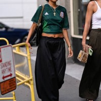 Guest is seen wearing a green Adidas collab t-shirt, Willy Chavarria black and red hat, black pants with a black and gold chain bag outside the Willy...