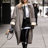 Guest is seen wearing a plaid coat, white shirt, gray tie, black shorts and black knee high boots with black sunglasses outside the Sandy Liang show...