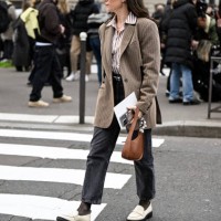 Guest is seen wearing a tan striped jacket, stripe shirt, gray pants and cream shoes with brown bag outside the Miu Miu show during the Womenswear...