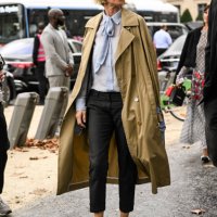 Guest is seen wearing a tan trench coat, blue blouse, black jeans and black outside the Chanel show during the Womenswear Spring/Summer 2024 as part...