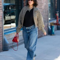 Guest is seen wearing printed black and brown jacket, black top, blue denim pant, cream shoes, brown sunglasses and carrying a red bag outside the...