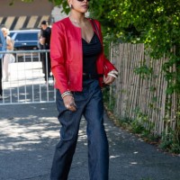 Guest is seen wearing red jacket, black top, dark blue denim pant, black boots, black sunglasses and carrying a red bag outside the Off-White show...