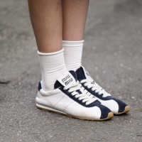 Guest is seen wearing white and blue Miu Miu sneakers with white socks outside the Miu Miu show during the Womenswear Fall/Winter 2025/2026 as part...