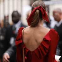 Guest seen outside Zuhair Murad show wearing red hair bow, red open back dress and Hermes Kelly bag in brown with gold hardware during the Haute...