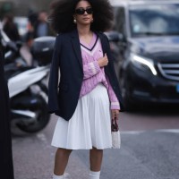 Guest seen wearing a black blazer jacket, purple Lacoste pullover, white skirt, socks, green sneaker, black shades and white bag outside Lacoste Show...