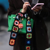 Guest seen wearing a brown wool coat, black and denim jeans pants, green Hermes Birkin bag with color printed statements, brown sunglasses and an...