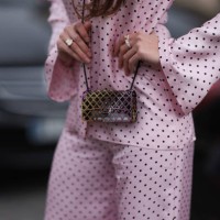 Guest seen wearing black sunglasses, a pink Chanel pyjama with flared pants and printed polka dots, a Chanel mini bag, platform black shoes, outside...