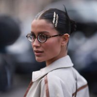 Guest seen wearing Miu Miu hair clips, Miu Miu brown round glasses and Miu Miu beige jacket with brown leather details outside Miu Miu Show during...