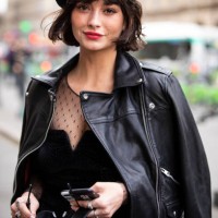 Guest, wearing a black mini dress, black leather jacket, black boots, black bag and hat, is seen outside Redemption on Day 4 Paris Fashion Week...