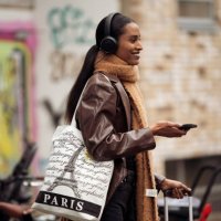 Guest wearing a brown leather jacket, brown long scarf, and black headphones outside Aeron during the Copenhagen Fashion Week Autumn/Winter 2023 on...
