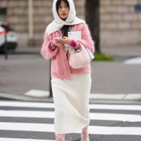 Guest wears a balaclava, a pink cardigan, a white skirt , floral print tights, sneakers shoes, outside Miu Miu , during the Womenswear Fall/Winter...