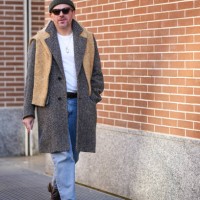 Guest wears a beanie hat, sunglasses, a beige scarf, a jacket, a white t-shirt, blue jeans, leather shoes, outside Fendi, during the Milan Fashion...