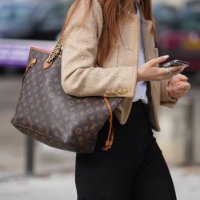 Guest wears a beige tweed jacket, a Vuitton large bag, black pants, outside Chanel, during the Womenswear Spring/Summer 2024 as part of Paris Fashion...