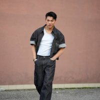 Guest wears a black Gucci denim opened jacket with cuffed short sleeves, a white t-shirt, black denim flared pants, black leather pointed shoes,...