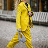 Guest wears a black large headband, a black t-shirt, a yellow oversized blazer jacket, yellow large suit pants, a gray satin with rhinestones mesh /...