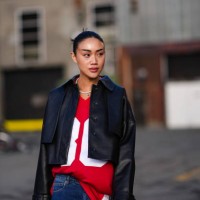 Guest wears a black leather jacket , red top, blue flared denim jeans pants , a red bag, outside Gestuz, during the Copenhagen Fashion Week AW24 on...