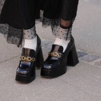 Guest wears a black polka dots print pattern tulle long skirt, white socks, black shiny varnished leather block heels / platform loafers, outside...