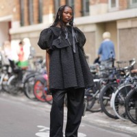 Guest wears a black textured ruffled dress, black pants, outside Cecilie Bahnsen, during the Womenswear Spring/Summer 2024 as part of Paris Fashion...
