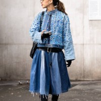 Guest wears a denim jacket embellished with blue rhinestones, a black leather belt, a denim round skirt, a black leather bag , black gloves and black...