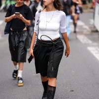 Guest wears a fitted white top with three-quarter sleeves. Sunglasses with a brown tint are worn, along with hoop earrings and a delicate chain...