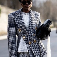Guest wears a gold hair accessor, a white lace top, a black and white checked jacket with gold buttons, a black bag, black gloves and a white tulle...