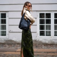 Guest wears a golden jacket, a green leather long skirt, red sneakers shoes, a black leather bag, outside Lovechild 1979, during the Copenhagen...
