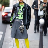 Guest wears a green necklace, a green printed t-shirt, a black leather jacket, a silver belt, a grey skirt, fluo green sunglasses, yellow tights and...