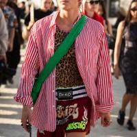 Guest wears a leopard print top, red striped shirt, sporty shorts and green bag, outside Casablanca, during the Womenswear Spring/Summer 2024 as part...