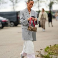 Guest wears a pale gray long blazer jacket, a white striped print pattern long jacket, pale pink puffy pants, gray sneakers, a beige with embroidered...