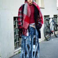 Guest wears a red and grey checked knitted maxi scarf, a red sweater, a red, black and grey checked coat, a white belt and denim ripped wide leg...
