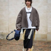 Guest wears a silver large chain necklace, a white pearls necklace, a white with black logo print pattern t-shirt from Jil Sander, a dark gray...