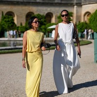 Guest wears a sleeveless yellow dress with a draped neckline and gathered waist detail. The fabric appears lightweight and flowing. Accessories...